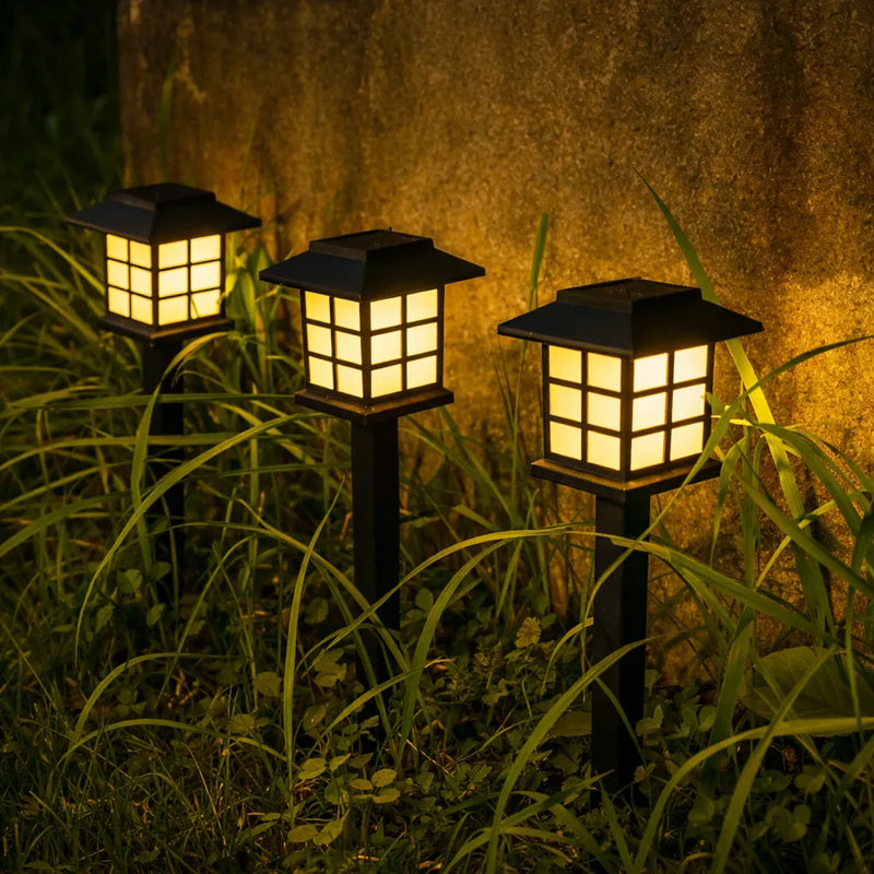 Warm white solar lantern garden stake lights glowing at night among garden plants, decorative solar pathway and border lights for Australian gardens and outdoor areas